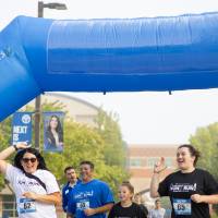 A family running through a blue inflatable finish line